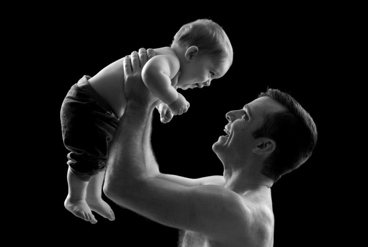 Far løfter stolt sin lille søn, månedsbillede i sort-hvidt med sort baggrund