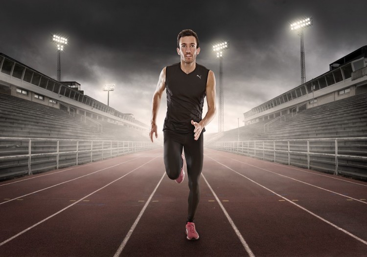 Billede af mandlig løber i sort løbeløj og pink løbesko løber på atletikbane