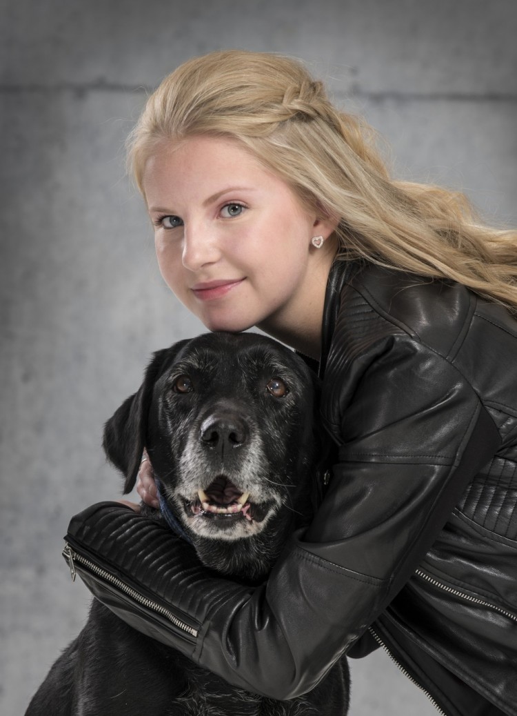 Billede af konfirmandinde i sort læderjakke sammen med en sort hund