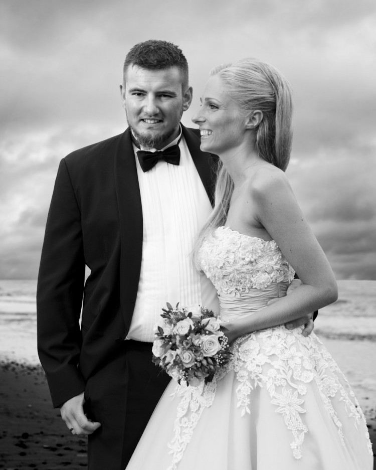Sort-hvidt bryllupsbillede – brudeparret står på en strand