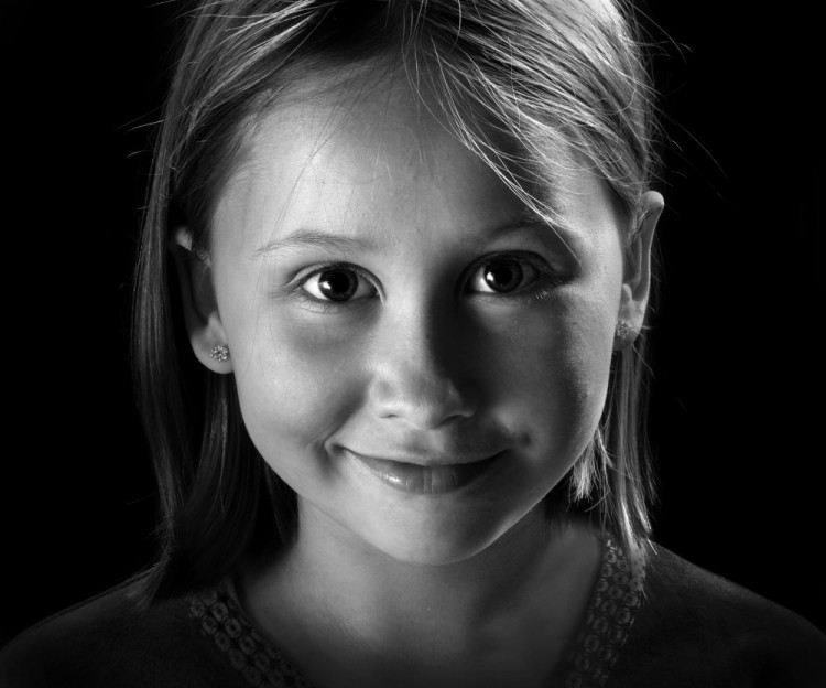 Børneportræt, der viser en piges ansigt tæt på og med sort baggrund