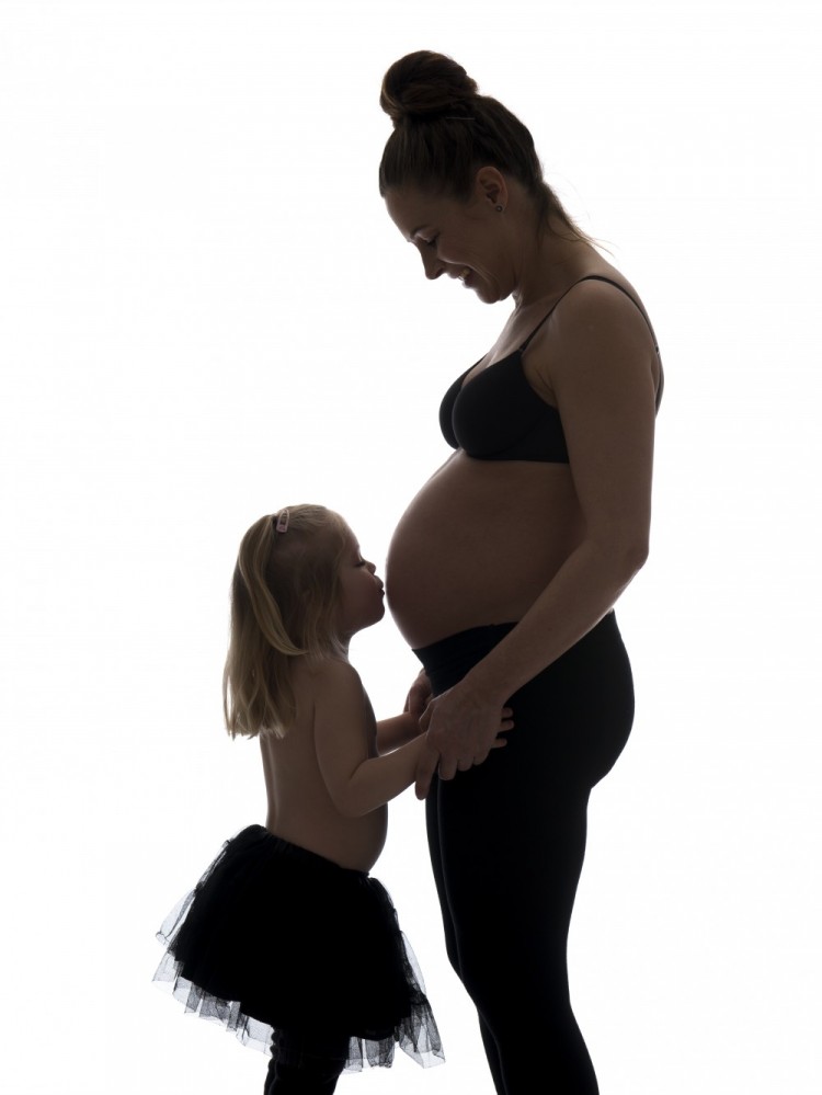 Graviditetsbillede af gravid mor og datter, der kysser maven - begge i sort...