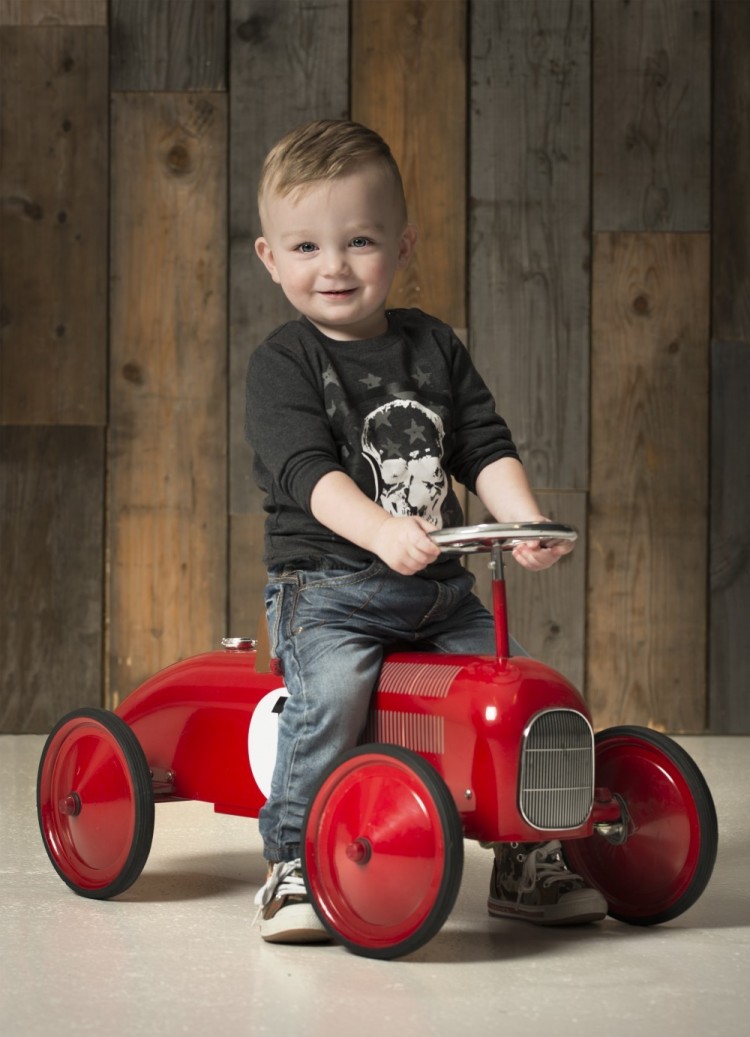 Fotografi af dreng på 2-3 år, der kører på en lille rød retrobil
