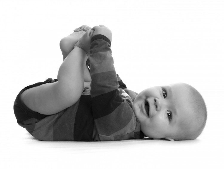 Månedsfoto i sort-hvid af lille dreng, der ligger på ryggen og holder fast i sine fødder