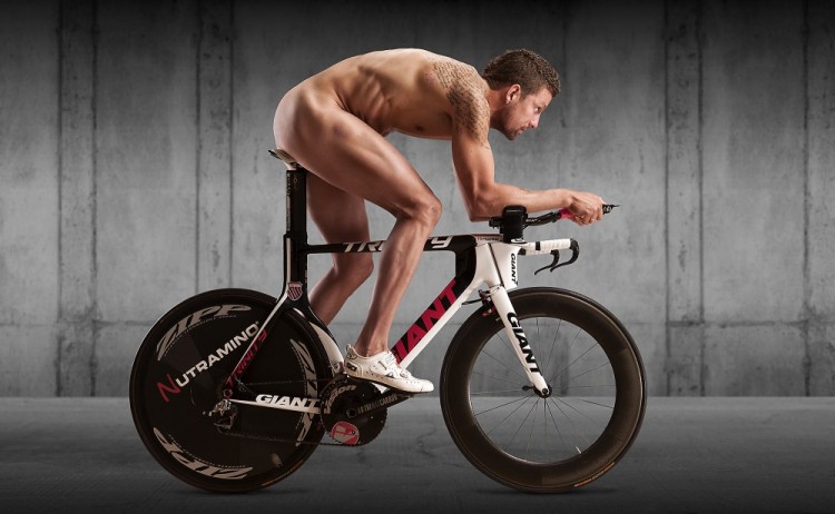 Foto af nøgen mand med tatoveringer sidder på racercykel – kun iført cykelsko